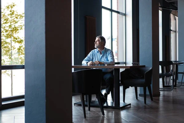 Hombre de negocios pensativo bebiendo café en la cafetería y mirando hacia otro lado . —  Fotos de Stock