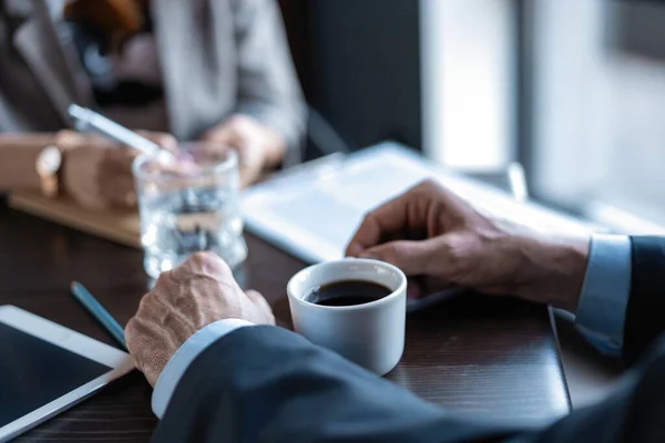 Nahaufnahme eines Mannes mit einer Tasse Kaffee und seinem Geschäftspartner in einem Restaurant während eines Geschäftsessens — Stockfoto