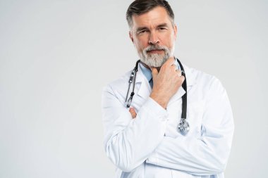 Neşeli olgun doktor kameraya, sağlık hizmetlerine ve tıbba poz veriyor ve gülümsüyor.