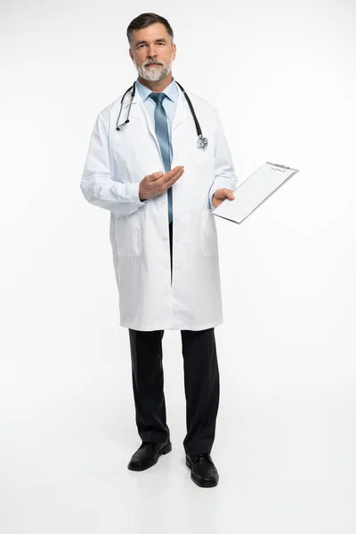 Helkroppsbild av en mogen läkare som håller ett anteckningsblock, på vit bakgrund. — Stockfoto