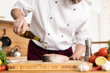 Şef taze balık somonu, alabalık, deniz tuzu ve sebze serpiştiriyor. Yatay fotoğraf. Sağlıklı ve vejetaryen yemekleri, temiz yemekler, restoranlar, otel işleri....