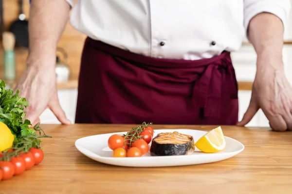 Chef mit Sorgfalt Fertiggericht auf Teller, Fisch mit Gemüse — Stockfoto