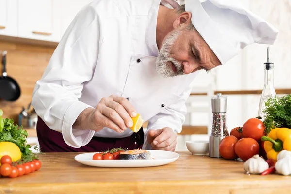 Chef con diligencia acabado plato en plato, pescado con verduras — Foto de Stock