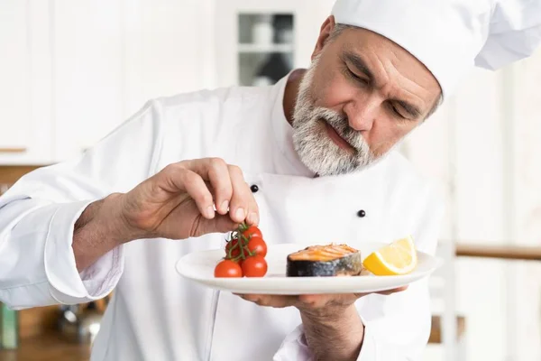 Chef met ijverig afwerken schotel op bord, vis met groenten — Stockfoto