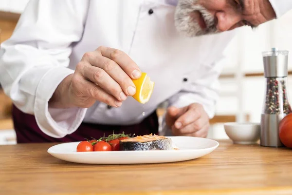 Chef mit Sorgfalt Fertiggericht auf Teller, Fisch mit Gemüse — Stockfoto