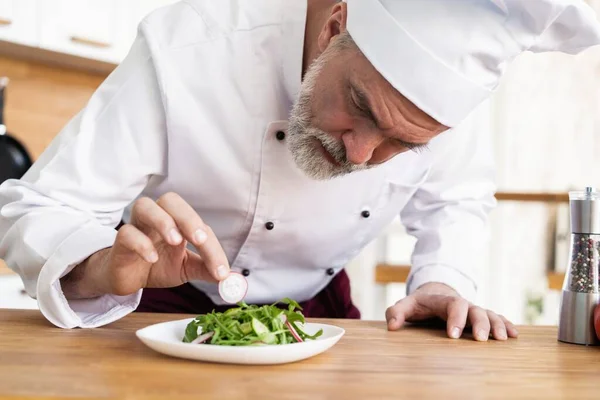 Chef masculino decoración guarnición plato de ensalada preparada en el plato en el restaurante cocina comercial . — Foto de Stock