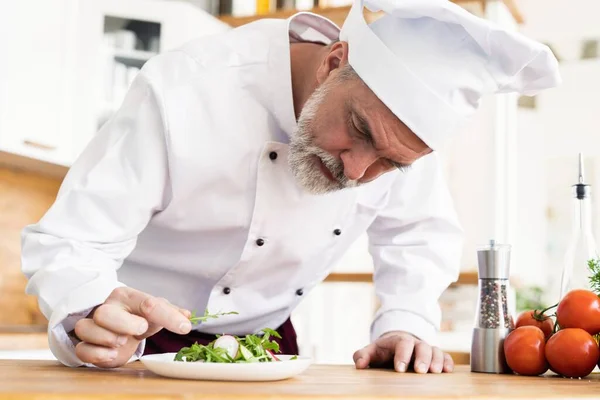 Mannelijke kok chef-kok versieren garnering bereid salade schotel op de plaat in restaurant commerciële keuken. — Stockfoto