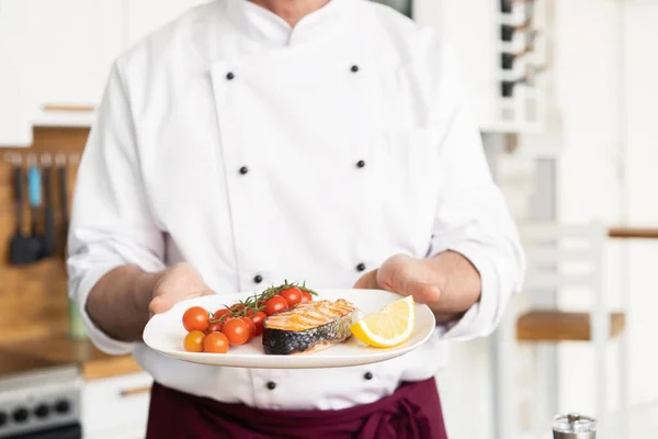 Chef mit Sorgfalt Fertiggericht auf Teller, Fisch mit Gemüse — Stockfoto