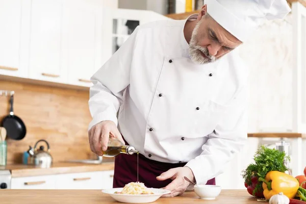 Chef reibt Käse mit frischen Nudeln auf den Teller. — Stockfoto