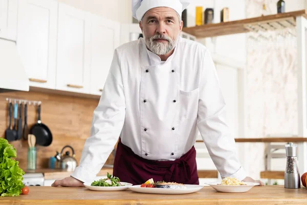 Aantrekkelijke Kaukasische chef-kok staand in een restaurantkeuken — Stockfoto