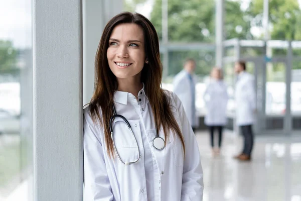 A kórházban álló fehér kabátos fiatal doktornő portréja. — Stock Fotó