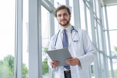 Erkek Doktor elinde dosyayla hastanede duruyor..