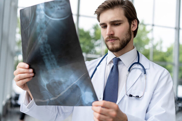 hospital doctor holding patients x-ray film, radiologist studying x-ray results.
