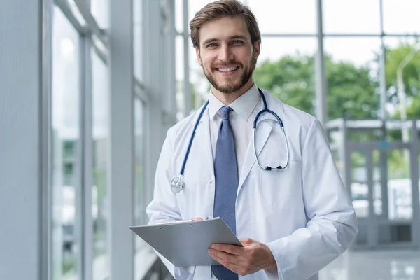 Médico masculino de pé com pasta no hospital . — Fotografia de Stock