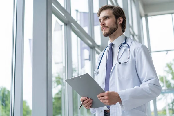 Doctor masculino de pie con carpeta en el hospital . — Foto de Stock