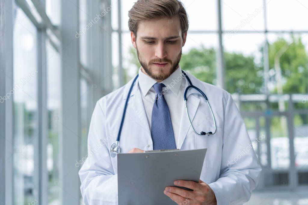 Male Doctor standing with folder in hospital.