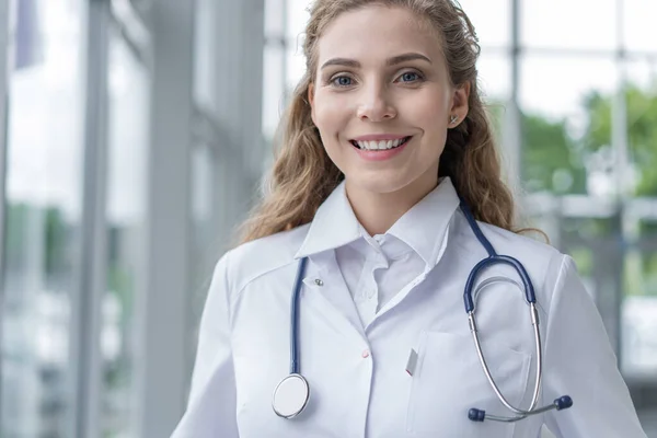 A kórházban álló fehér kabátos fiatal doktornő portréja. — Stock Fotó
