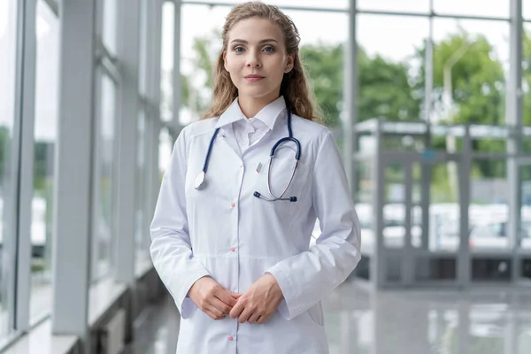 하얀 코트를 입고 병원에 서 있는 젊은 여자 의사의 모습. — 스톡 사진
