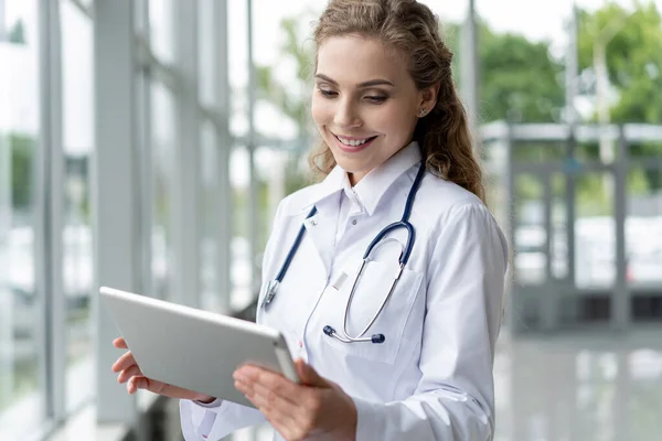 건강, 기술 및 의학 개념 - 평판 pc 컴퓨터에서 노트를 찍는 청진기를 가진 여성 의사 미소. — 스톡 사진