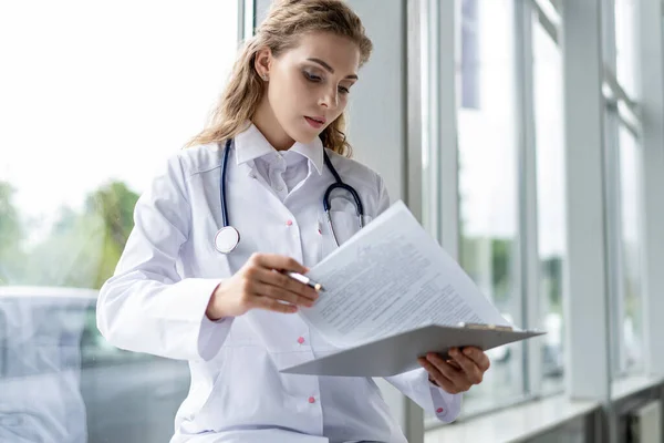 Dokter wanita berdiri dengan folder di rumah sakit. — Stok Foto