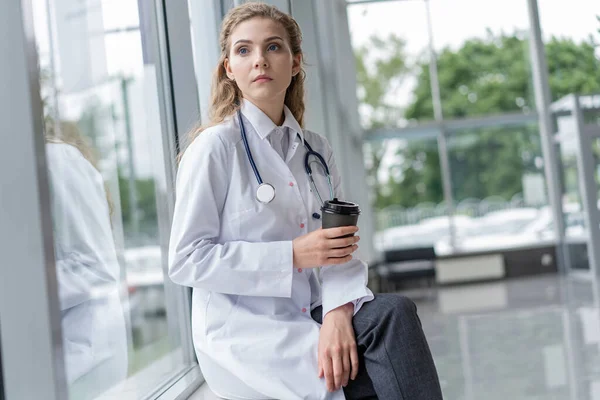 Porträt einer müden, erschöpften Krankenschwester oder Ärztin, die im Krankenhaus eine Kaffeepause einlegt. COVID-19, Coronavirus-Pandemie. — Stockfoto