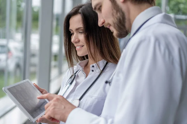 Férfi orvos segítségével digitális tabletta a női kolléga a kórházban, együtt dolgoznak. — Stock Fotó