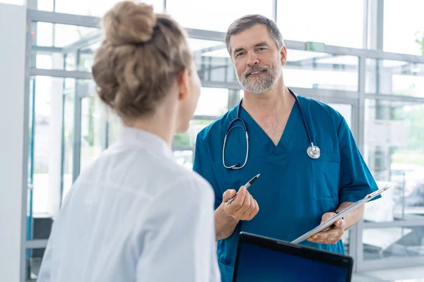 Médico en discusión con la enfermera en la estación de enfermeras o en la recepción del hospital . — Foto de Stock