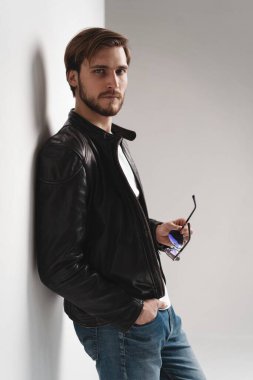 Moda adamı, yakışıklı, ciddi, güzel erkek model portresi deri ceket, beyaz arka planda genç bir adam..