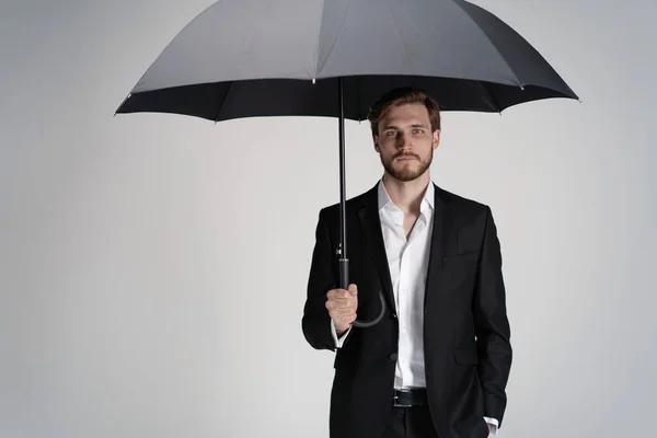 黒い傘の下に立つスーツのビジネスマン. — ストック写真