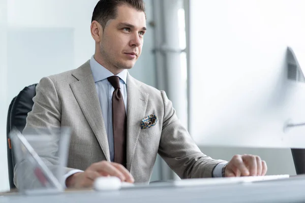 Jonge werknemer op zoek naar computer monitor tijdens de werkdag in kantoor. — Stockfoto