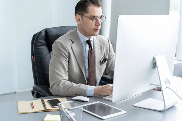 Joven empleado mirando el monitor de la computadora durante la jornada laboral en la oficina. — Foto de Stock