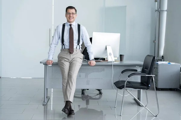 Portret van een zelfverzekerde jonge zakenman die alleen staat in een groot modern kantoor vlakbij zijn werkplek. — Stockfoto