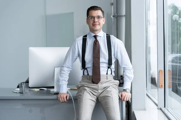 Porträt eines selbstbewussten jungen Geschäftsmannes, der allein in einem großen modernen Büro in der Nähe seines Arbeitsplatzes steht. — Stockfoto