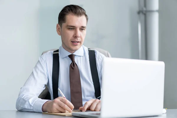 Schöner Geschäftsmann arbeitet im Büro mit Laptop. — Stockfoto