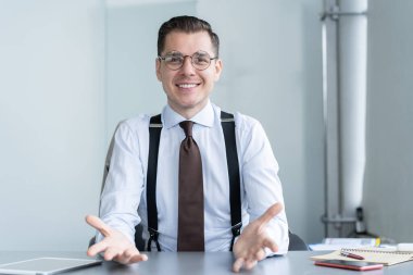 Gülümseyen işadamı masa başında oturmuş web kamerasında müşteriyle görüntülü konuşma yapıyor, motivasyon koçu internet üzerinden konuşma yapıyor.