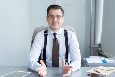 Gülümseyen işadamı masa başında oturmuş web kamerasında müşteriyle görüntülü konuşma yapıyor, motivasyon koçu internet üzerinden konuşma yapıyor.