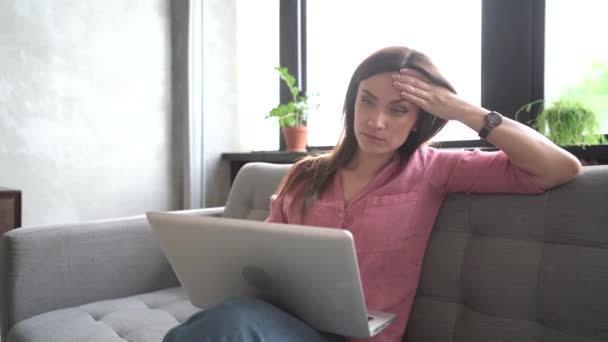 Sorrindo jovem mulher sentada no sofá usando notebook laptop olhando para a mensagem de digitação de tela, senhora feliz conversando no computador navegando internet redes sociais estudando ou trabalhando on-line em casa. — Vídeo de Stock