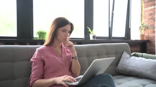 Mujer joven sonriente sentada en el sofá usando portátil portátil mirando el mensaje de escritura de pantalla, señora feliz charlando en la computadora navegando por Internet redes sociales estudiando o trabajando en línea en casa. — Vídeos de Stock