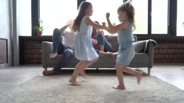 Mutlu bir aile ya da dört kişi hafta sonu yaşam tarzının tadını çıkartıyor. Modern iç mekanlarda rahatlıyorlar. Genç ebeveynler kanepeye oturup dizüstü bilgisayar kullanıyorlar..