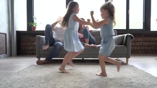 Gelukkig gezin of vier genieten van weekend levensstijl ontspannen in modern interieur, jonge ouders paar zitten op de bank met behulp van laptop grappige kleine leuke actieve kinderen kinderen lopen spelen in modern huis. — Stockvideo