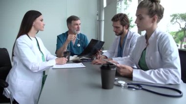 Bir grup doktor tıbbi konferansta röntgene bakıyor, sorunları tartışıyorlar.