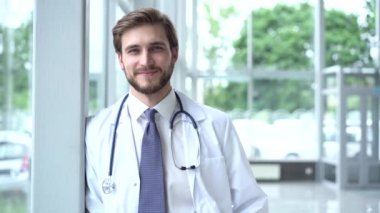 Hastane koridorundaki işinden memnun gülümseyen erkek doktorun portresi. Tıp, teknoloji, sağlık ve insan kavramı, hastane.