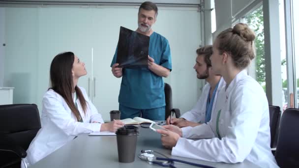 Orvosok csoportja vizsgálja a röntgent az orvosi konferencián, megvitatják a kérdéseket — Stock videók