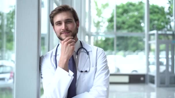 Porträtt av leende manlig läkare nöjd med sitt jobb i en korridor på ett sjukhus. Begreppet medicin, teknik, hälsovård och människor, sjukhus. — Stockvideo