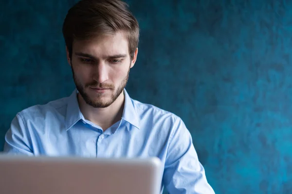 Felice giovane uomo d'affari utilizzando il computer portatile alla scrivania del suo ufficio. — Foto Stock