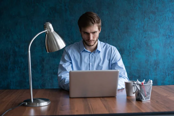 Jovem empresário feliz usando laptop em sua mesa de escritório. — Fotografia de Stock