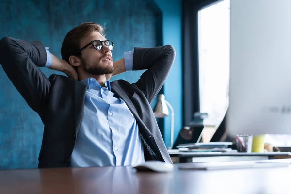 Homme d'affaires souriant heureux dans des lunettes et chemise bleue relaxant au bureau après une dure journée de travail. — Photo