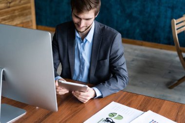 Dijital tablet üzerinde çalışan gülümseyen adam.