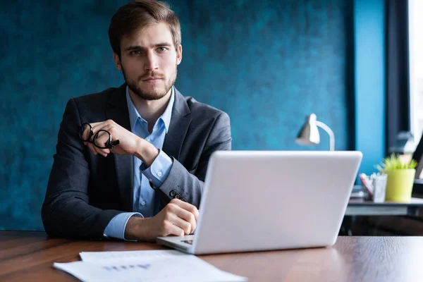 Glücklicher junger Geschäftsmann mit Laptop am Schreibtisch. — Stockfoto