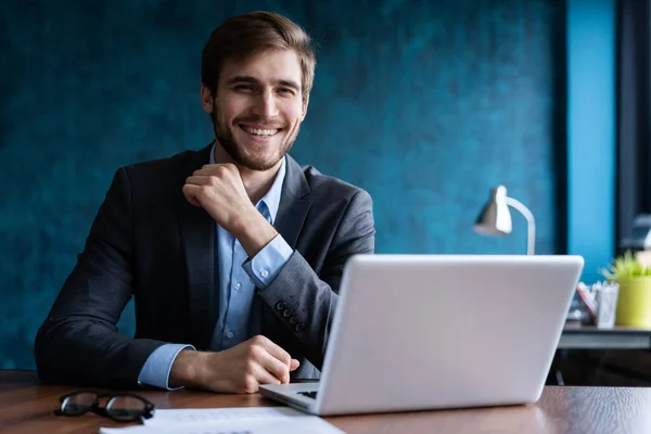 Glücklicher junger Geschäftsmann mit Laptop am Schreibtisch. — Stockfoto